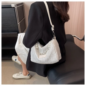 Detail of white pleated shoulder bag featuring pearl chain and fashion fabric label