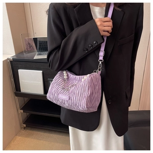 Detail of purple pleated underarm bag featuring pearl handle and metal chain accents