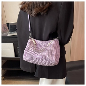 Detail of purple pleated cloud bag with pearl chain shown worn over a shoulder