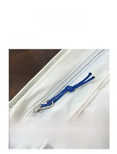 Detailed macro view of the smooth metal zipper with a blue cord pull on white fabric