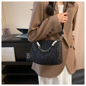 Detail of black matelassé shoulder bag with elegant pearl and silver chain decoration