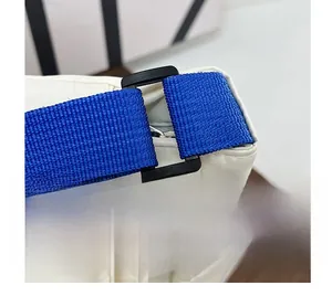 Close-up of the durable blue woven strap attached to an off-white nylon crossbody bag
