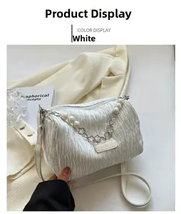Detail of white pleated barrel bag with pearl chain and silver floral accents