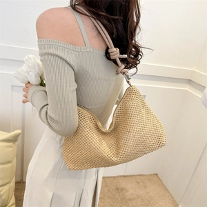 Elegante borsa hobo in paglia beige con tracolla in pelle marrone annodata indossata da modella