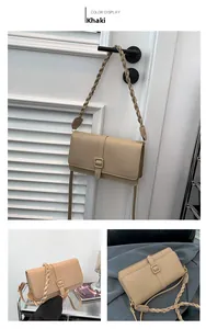 Detalle del bolso bandolera de piel caqui con correa tejida y hebilla cuadrada en la solapa