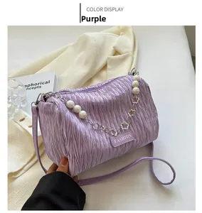Detail of light purple pleated shoulder bag with pearl chain on beige blazer