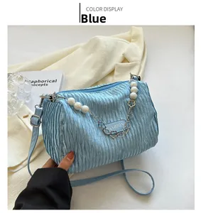 Blue pleated shoulder bag with elegant pearl chain strap shown on blazer background