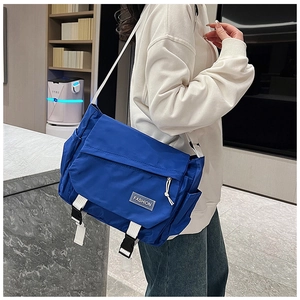 Side view of large navy messenger bag with white straps worn by a male model