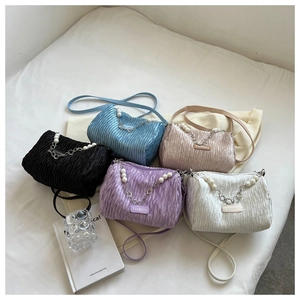 Detailed top view of five pleated crossbody bags with pearl straps and metal chains