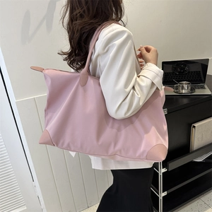 Bolso de viaje rosa de nailon con asas de cuero mostrado en un entorno de oficina moderno