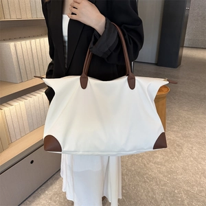 Bolso tote de nailon blanco crema con asas de cuero marrón llevado por una modelo