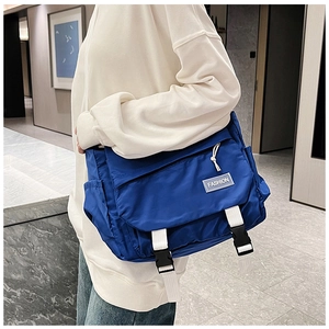 Close-up of navy blue crossbody bag with white buckles and fashion label detail