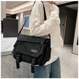 Model wearing a large black messenger bag in wear-resistant nylon with buckle closure