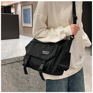 Detail of high-capacity black nylon messenger bag with buckle closure and side pocket