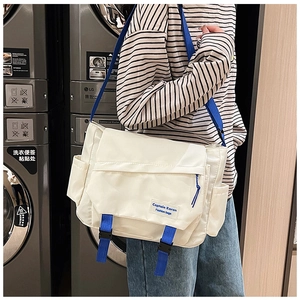 Detail of white nylon messenger bag with blue buckle strap and industrial style design