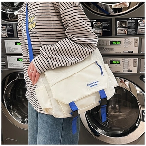 Close-up of white crossbody bag with blue straps and buckle detail shown on a model