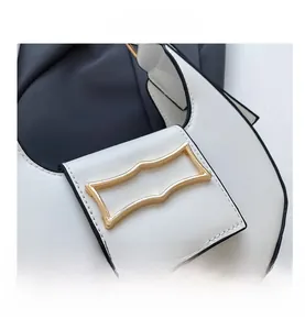 Close-up of minimalist white crescent bag with gold buckle and black oil edge details