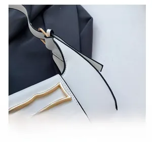 Macro detail of creamy white leather handbag with wave-shaped gold metal buckle