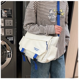 Detail of white canvas messenger bag with blue adjustable strap worn by a model
