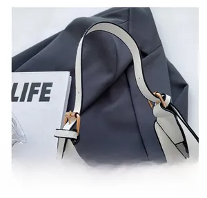 Detail of adjustable strap with gold buckles and black oil edge on white leather bag