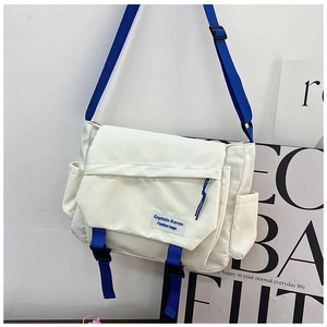 Detail of crossbody bag showing blue strap and white nylon fabric with plastic buckle