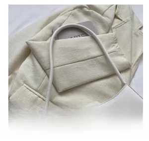 Detail of white baguette bag featuring a large square buckle and smooth leather texture