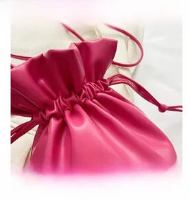 Close-up of fuchsia drawstring bucket bag with fine PU leather texture and pleats