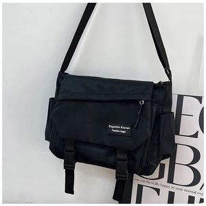 Detail view of black canvas messenger bag with durable buckles and side pockets
