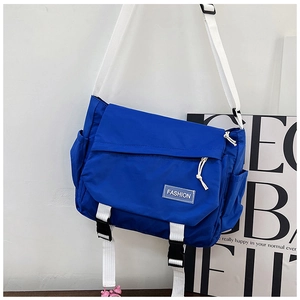 Detail of royal blue messenger bag with white fashion tag and adjustable strap