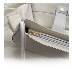 Detail of smooth gold zipper and ivory leather material on a minimalist handbag