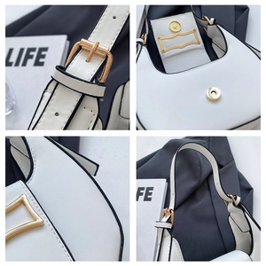 Macro detail of white leather crescent bag showing black trim and golden hardware