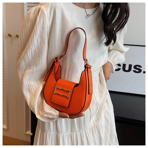 Detail of a bright orange leather hobo bag with a modern golden rectangular buckle detail