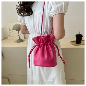 Detail of rose pink leather bucket bag with gold hardware on white dress model