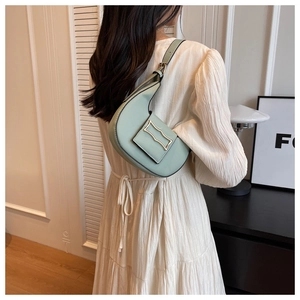 Detail of mint green crescent shoulder bag with gold metal buckle on a white dress