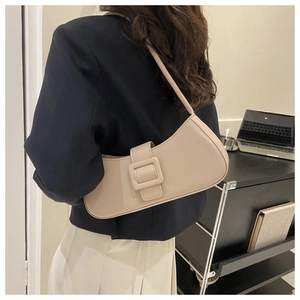 Close-up of a beige faux leather underarm bag with a large square buckle on a model