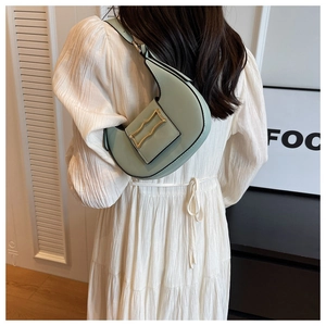 Close-up of a light green crescent shoulder bag with a stylish golden wave buckle