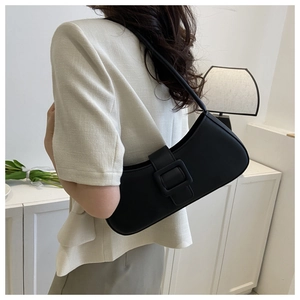Vue latérale d'un sac baguette en cuir noir avec boucle carrée sur l'épaule d'un modèle