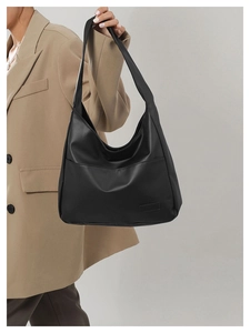 Close-up of a minimalist black leather tote bag featuring a large front pocket for daily use
