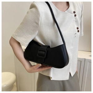 Detail shot of a minimalist black baguette bag with oversized decorative buckle and smooth leather