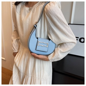 Light blue crescent shoulder bag with silver buckle worn by a model in beige dress