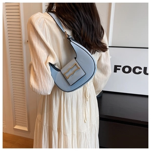 Detail of light blue hobo bag with gold buckle on a white pleated dress background