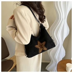 Detail view of a black shoulder bag featuring a large brown star patch and chain strap