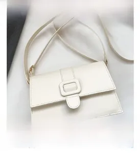 Detail view of cream white square crossbody bag with large matching buckle on flap