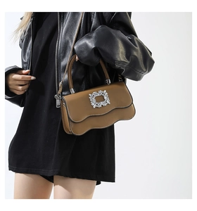 Détail du sac à main en cuir marron avec boucle en cristal sur un mannequin en veste en cuir