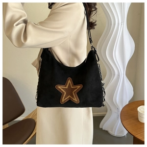 Detailed view of black matte tote bag featuring a gold glitter star patch and silver chain