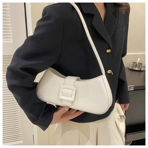 Détail d'un sac baguette blanc minimaliste avec boucle carrée sur un blazer noir chic