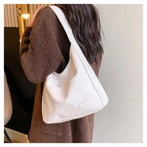 Close-up of white large capacity tote bag featuring a minimalist curved design and front pocket