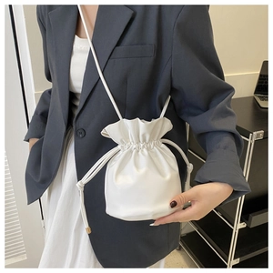 Close-up of white drawstring bucket bag with soft leather texture and slim shoulder strap