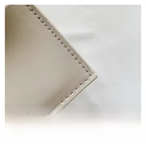 Close-up of premium cream faux leather texture and precise stitching on the square bag