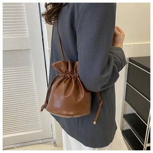 Brown pleated drawstring bucket bag styled with a grey blazer for a modern daily outfit